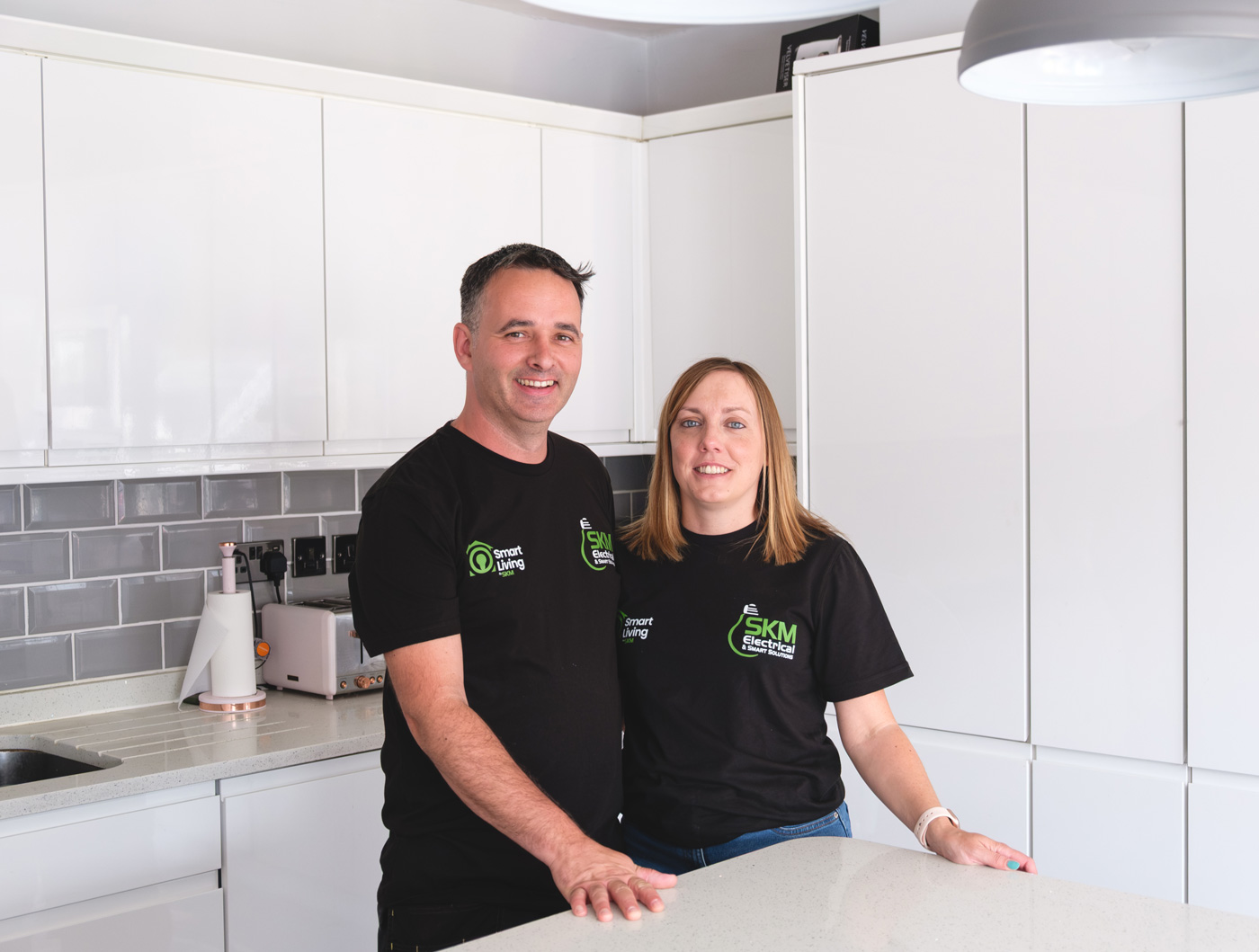 Spencer & Kirsty McNamara (owners of SKM Smart Living) stand together in a modern smart home kitchen